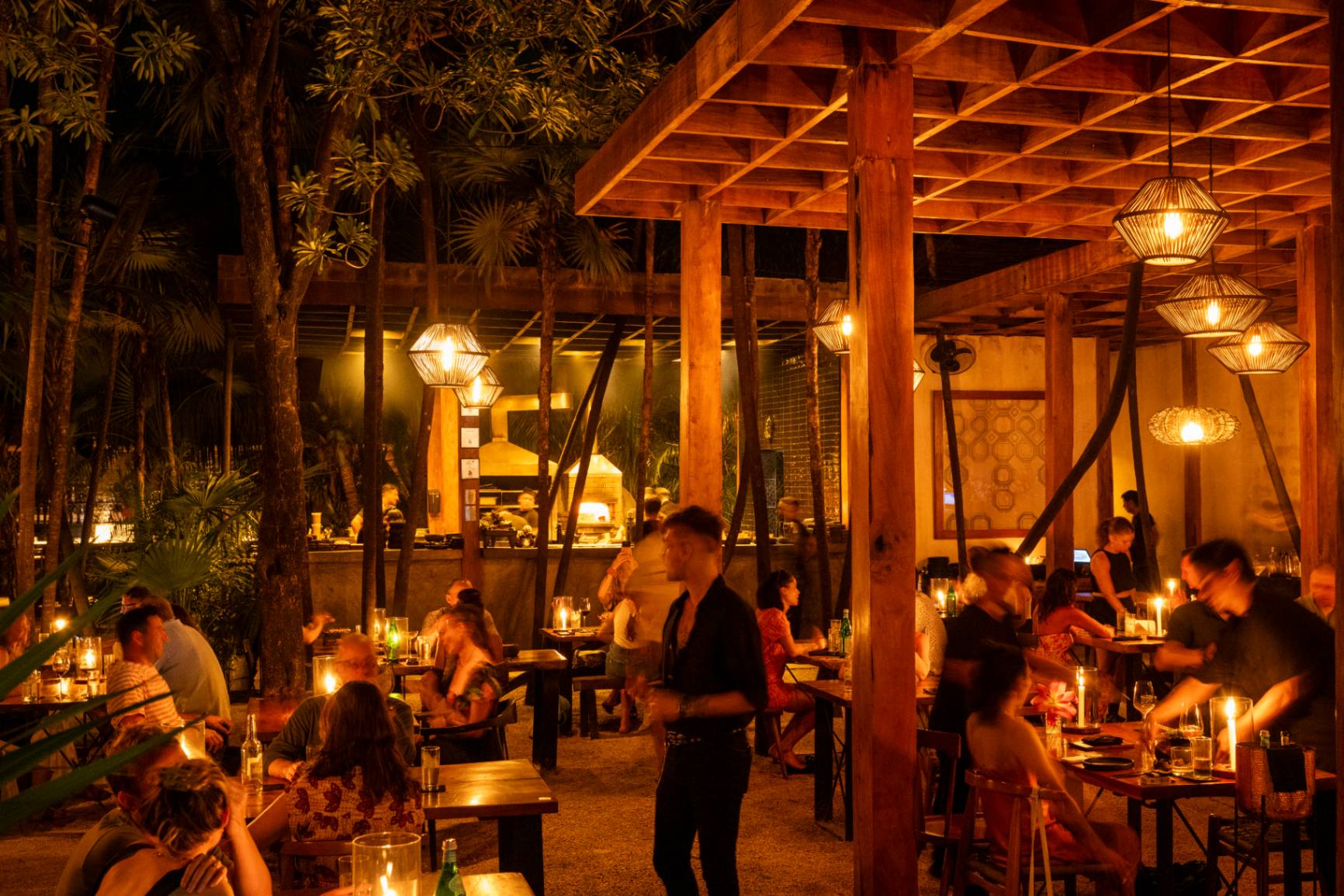 Mesas a la luz de las velas en la terraza de ARCA Tulum rodeada de selva
