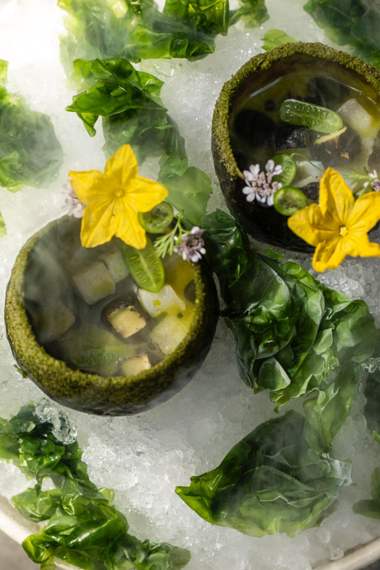 Aguachile de callo de hacha en cuencos verdes con flores de calabaza y hojas, ARCA Tulum