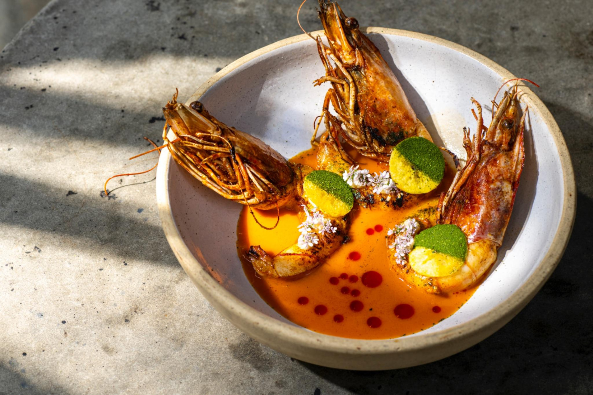Langostinos rostizados enteros en plato hondo blanco con salsa de plátano macho, ARCA Tulum